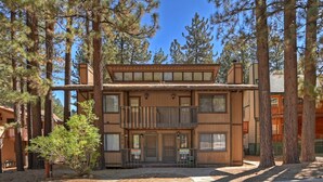 Un bâtiment en bois à deux étages, doté d’un balcon et entouré de grands pins.