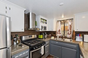 Een moderne keuken met roestvrijstalen apparatuur, een gasfornuis en een magnetron.