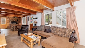 A cozy living room with a wooden ceiling, a sofa set, a coffee table, and a fireplace.