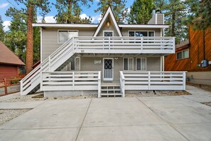 A two-story house with a front porch, a staircase, and a fenced deck area. - Tehama Cottage by Destination Big Bear : Close to Bear Mountain Resort & Zoo! Ping Pong Table! (Big Bear Lake)