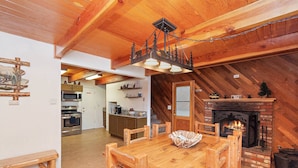 Un acogedor interior de cabaña con una mesa de comedor de madera, una chimenea y una zona de cocina.