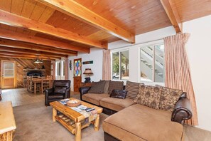A cozy living room with a wooden ceiling, a sofa, a coffee table, and a fireplace.