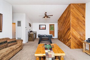 Een kamer met een houten tafel, een bank, een plafondventilator en een wand met een steenstrippatroon.