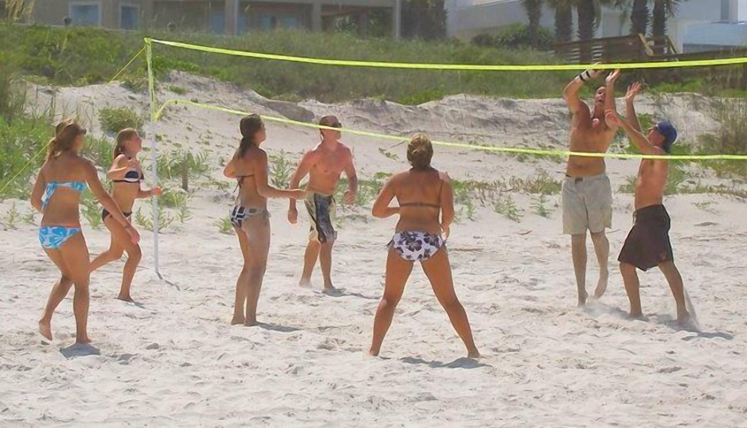 Jogo de voleibol de praia com jogadores de fato de banho.
