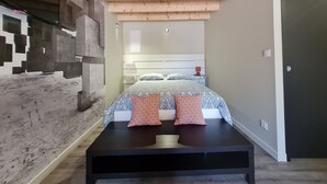 Quarto com cama, mesa de cabeceira e teto de madeira.
