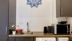 Een keuken met een spoelbak, een magnetron, een koffiezetapparaat en een vaatwasser.