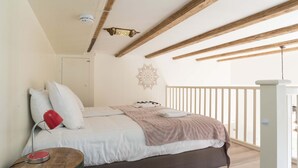 Une chambre à coucher comprenant un lit, une lampe de chevet, une tête de lit en bois, un élément décoratif mural et un balcon avec une balustrade.
