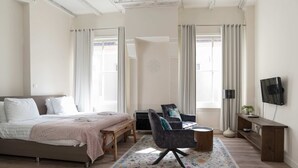 Ein Schlafzimmer mit Bett, Schreibtisch, Stuhl, Fernseher und Fenster.