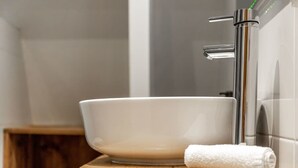 A bathroom with a white ceramic sink, a chrome faucet, and a wooden vanity.