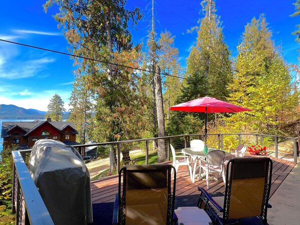 Une terrasse avec des meubles d’extérieur, un barbecue et un parasol rouge.