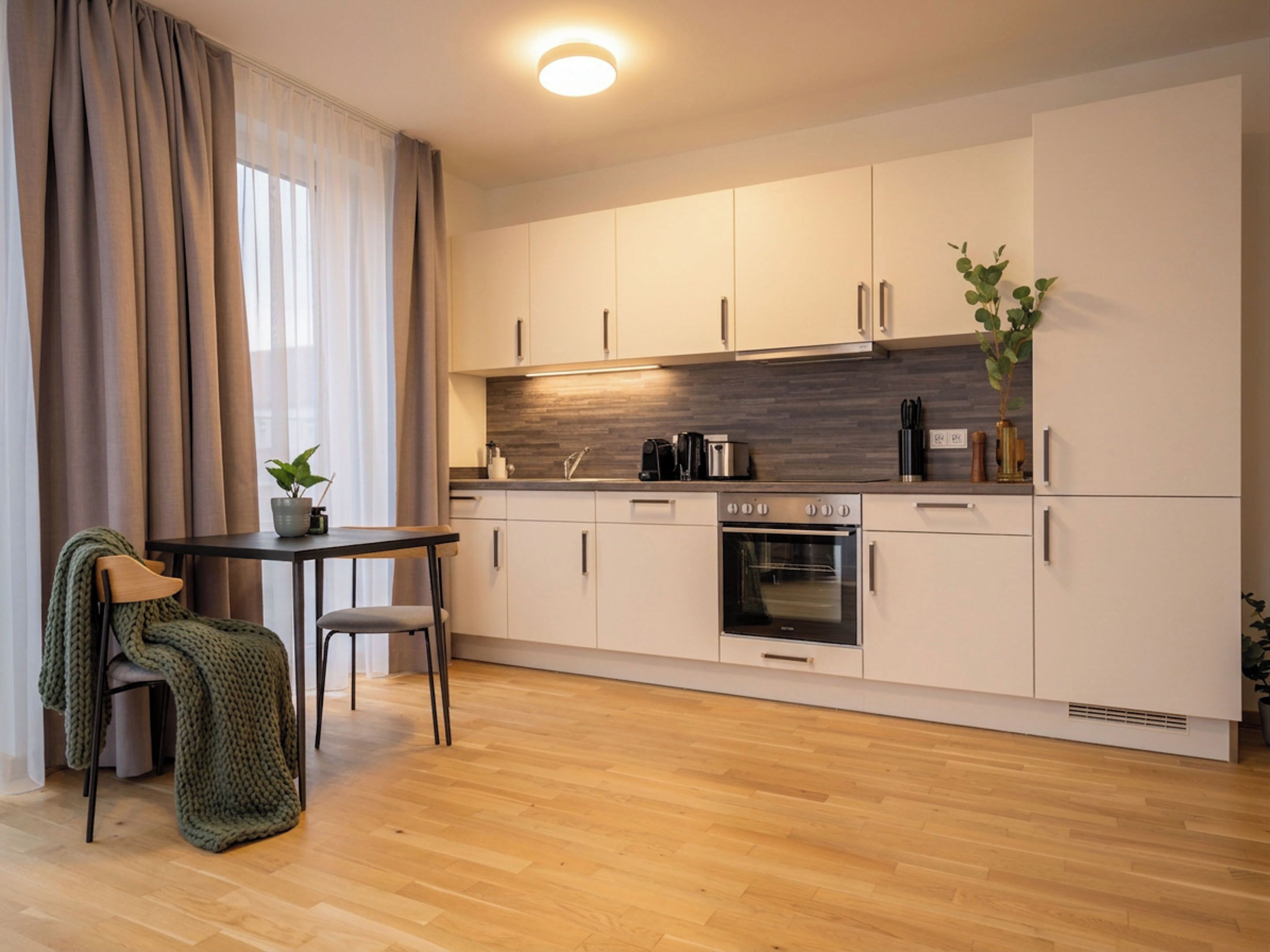 A modern kitchen with white cabinets, a wooden countertop, and a built-in oven.