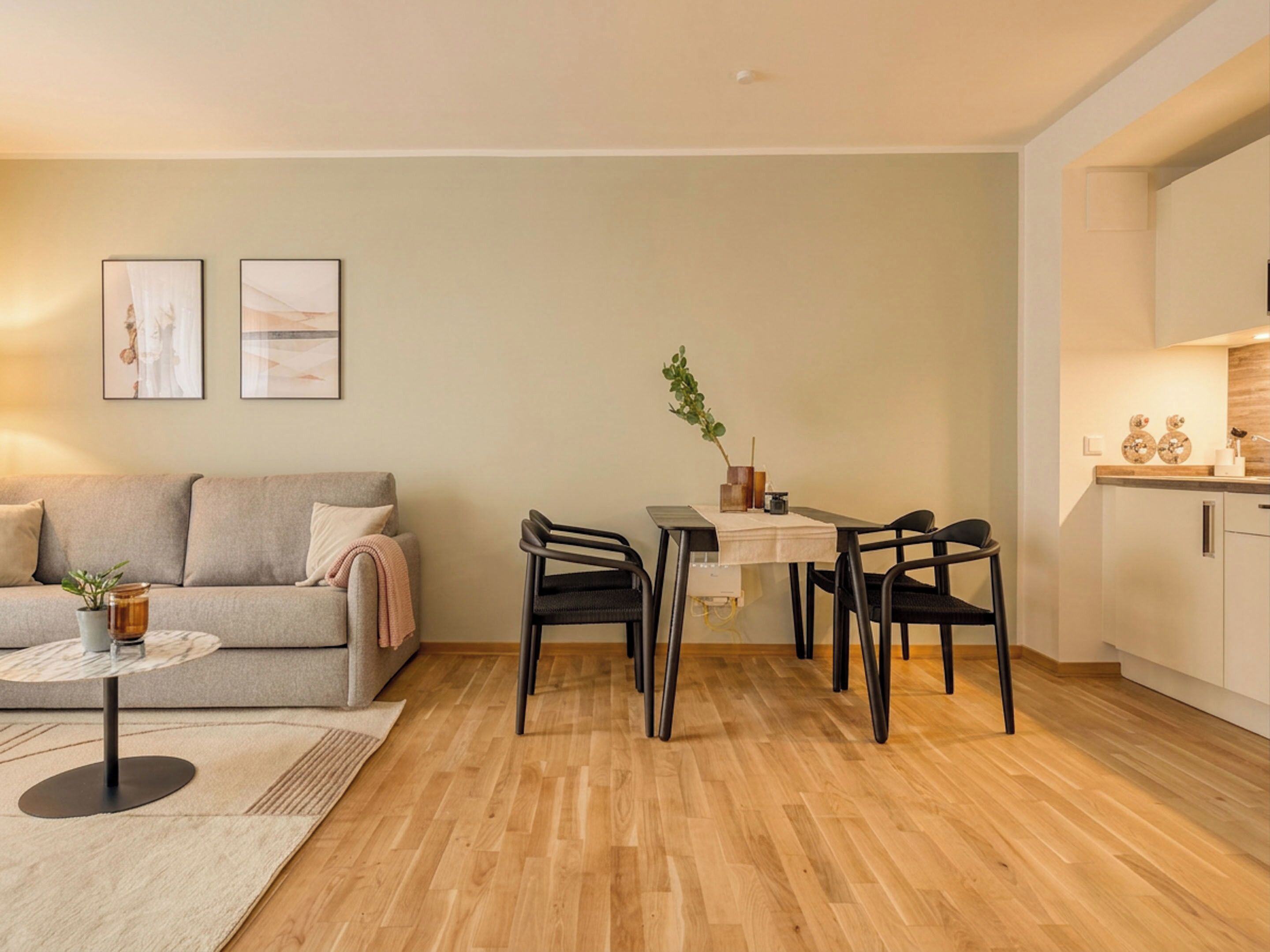 Een moderne woonkamer met een bank, salontafel en een eethoek met stoelen.
