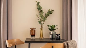 A dining area with a table, two chairs, a vase with a plant, and a candle holder. - Limehome Dresden Wallstraße (Dresden)