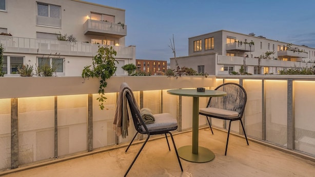 A rooftop terrace with a round table and two chairs, a view of modern buildings, and a clear sky. - Limehome Dresden Wallstraße (Dresden)