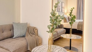 A modern living room with a sofa, a round marble table, a large mirror, and a plant. - Limehome Dresden Wallstraße (Dresden)