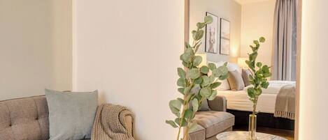 A modern living room with a sofa, a round marble table, a large mirror, and a plant.
