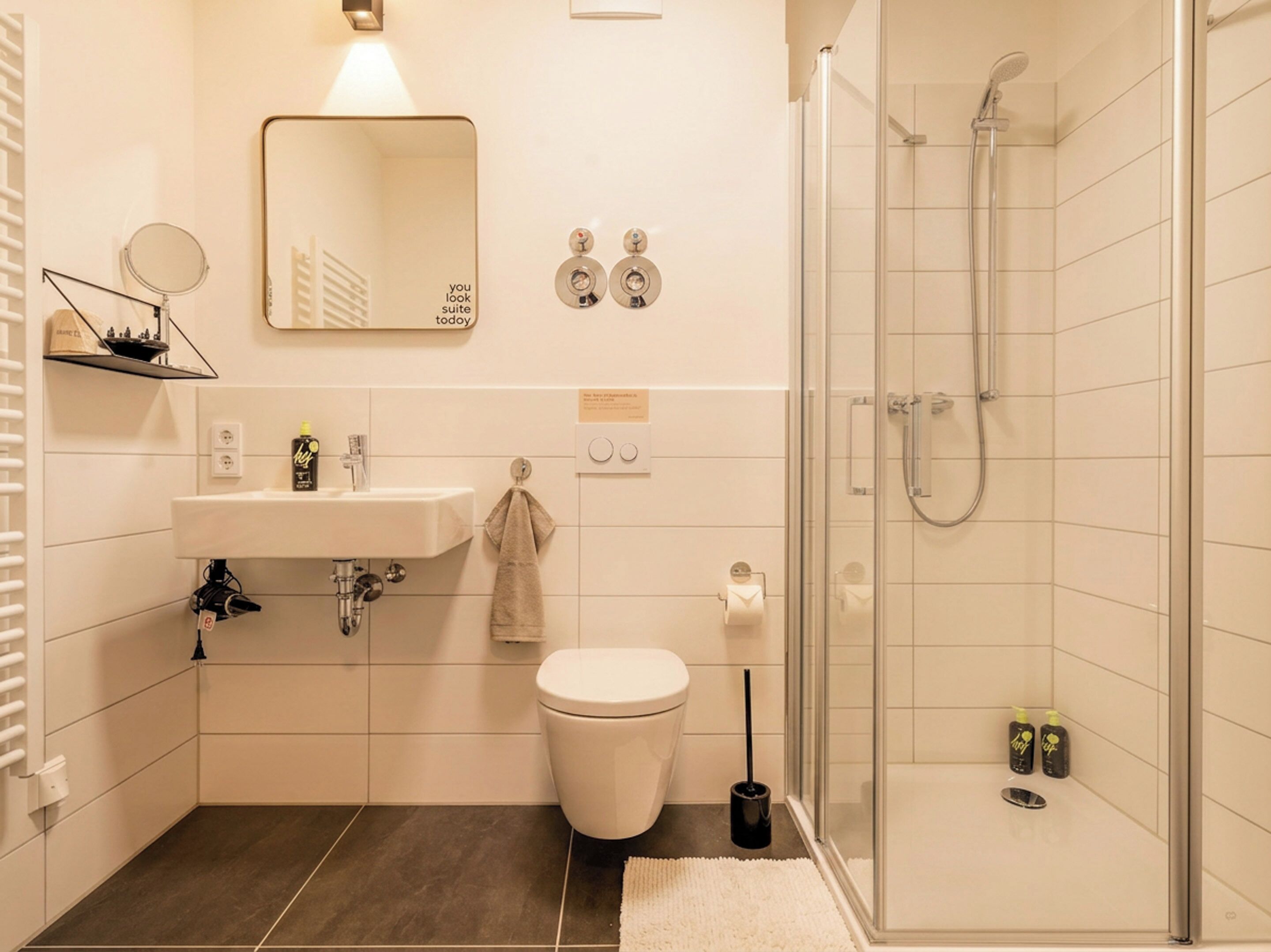 Un baño moderno con lavamanos, inodoro, espejo y ducha.