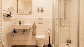 Un baño moderno con lavamanos, inodoro, espejo y ducha.