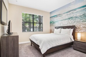 A bedroom with a bed, a window with blinds, a TV on a stand, and a mural of a beach scene. - Endless Summer at Solterra Resort by Shine Villas 079 (Davenport)