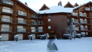 Un immeuble en bois à plusieurs étages, doté de balcons et d’une entrée centrale.