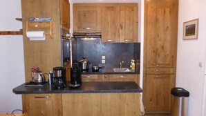 Une cuisine compacte avec des meubles en bois, un plan de travail noir et des appareils électroménagers en acier inoxydable.