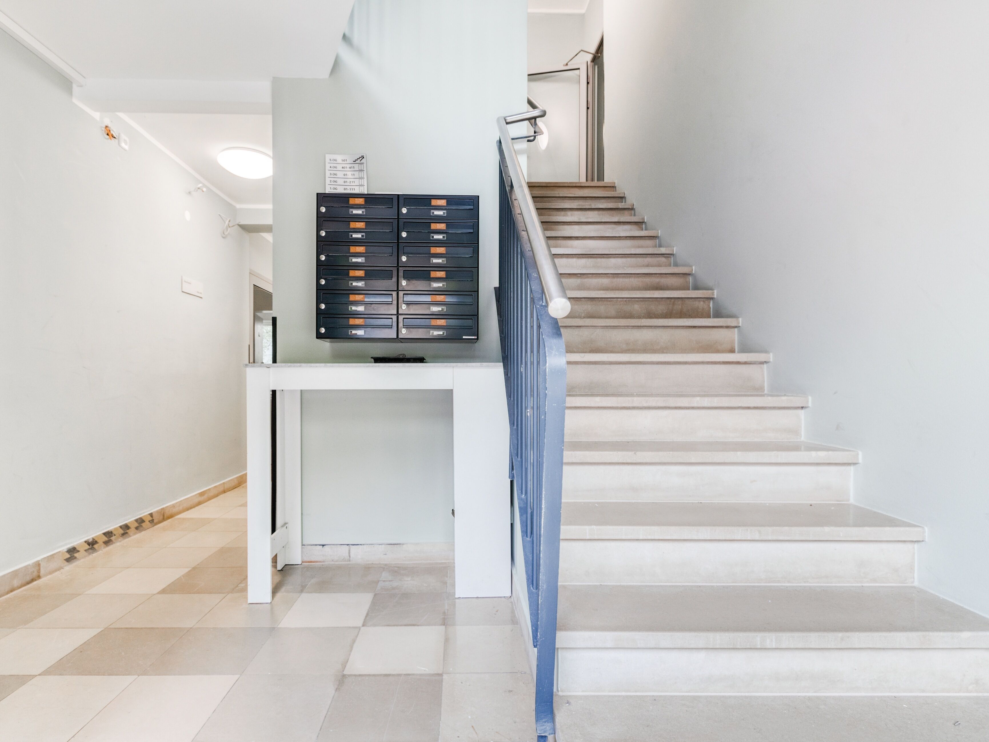 A staircase with a metal railing and a wall-mounted filing cabinet.