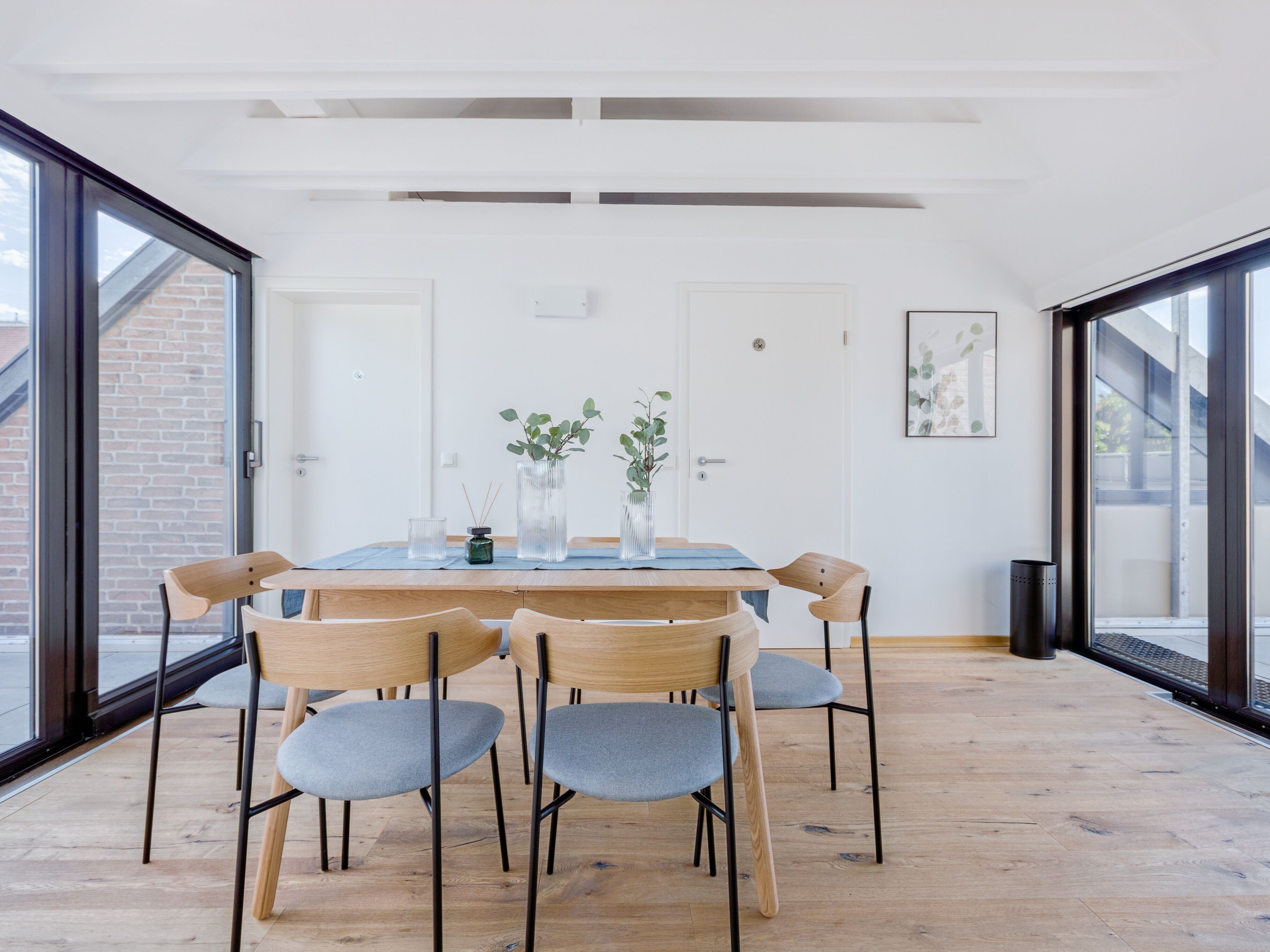 A dining area with a wooden table and chairs, a small plant, and a door with a window.