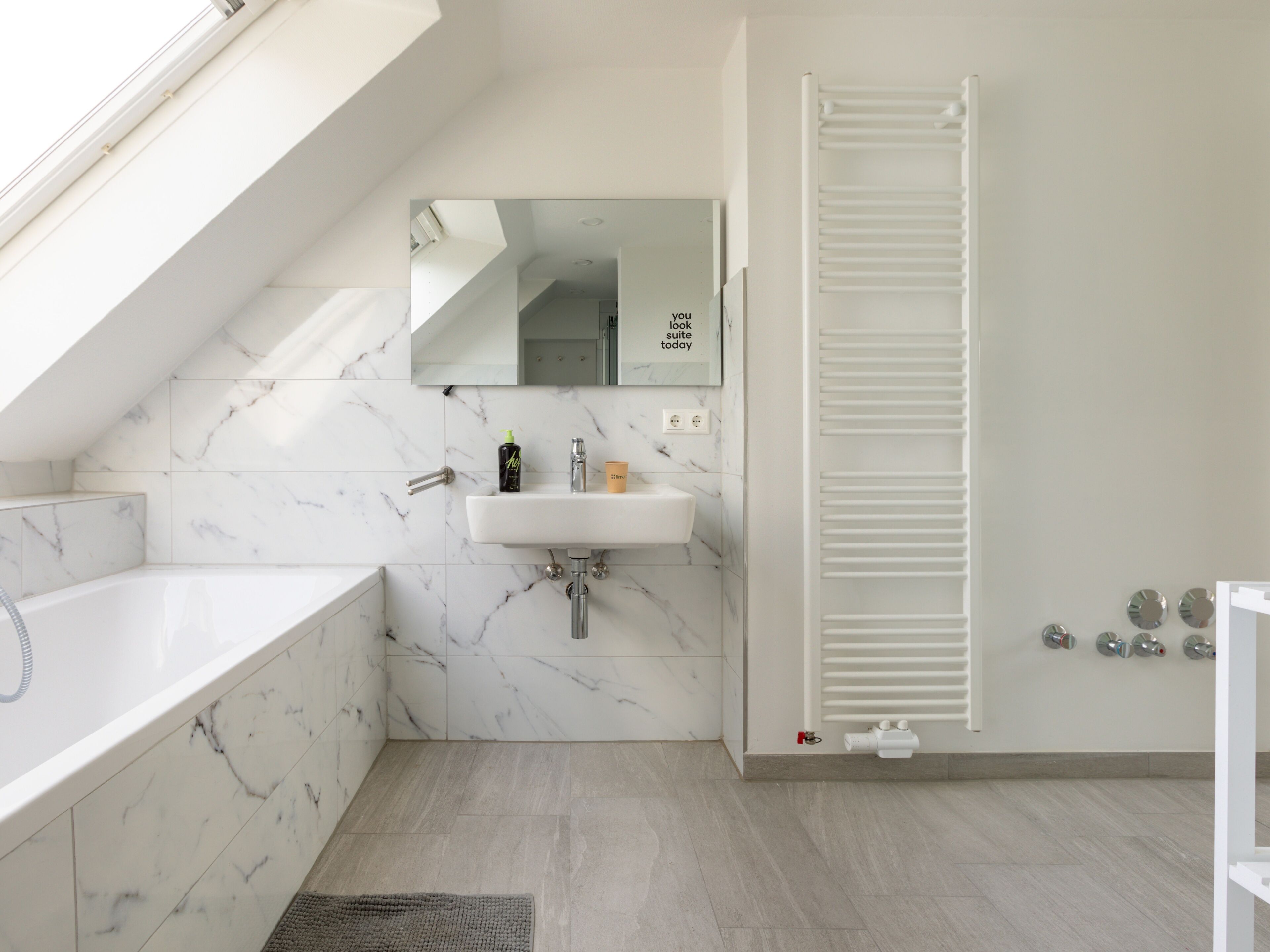 A modern bathroom with a white marble sink, a bathtub, and a walk-in shower.