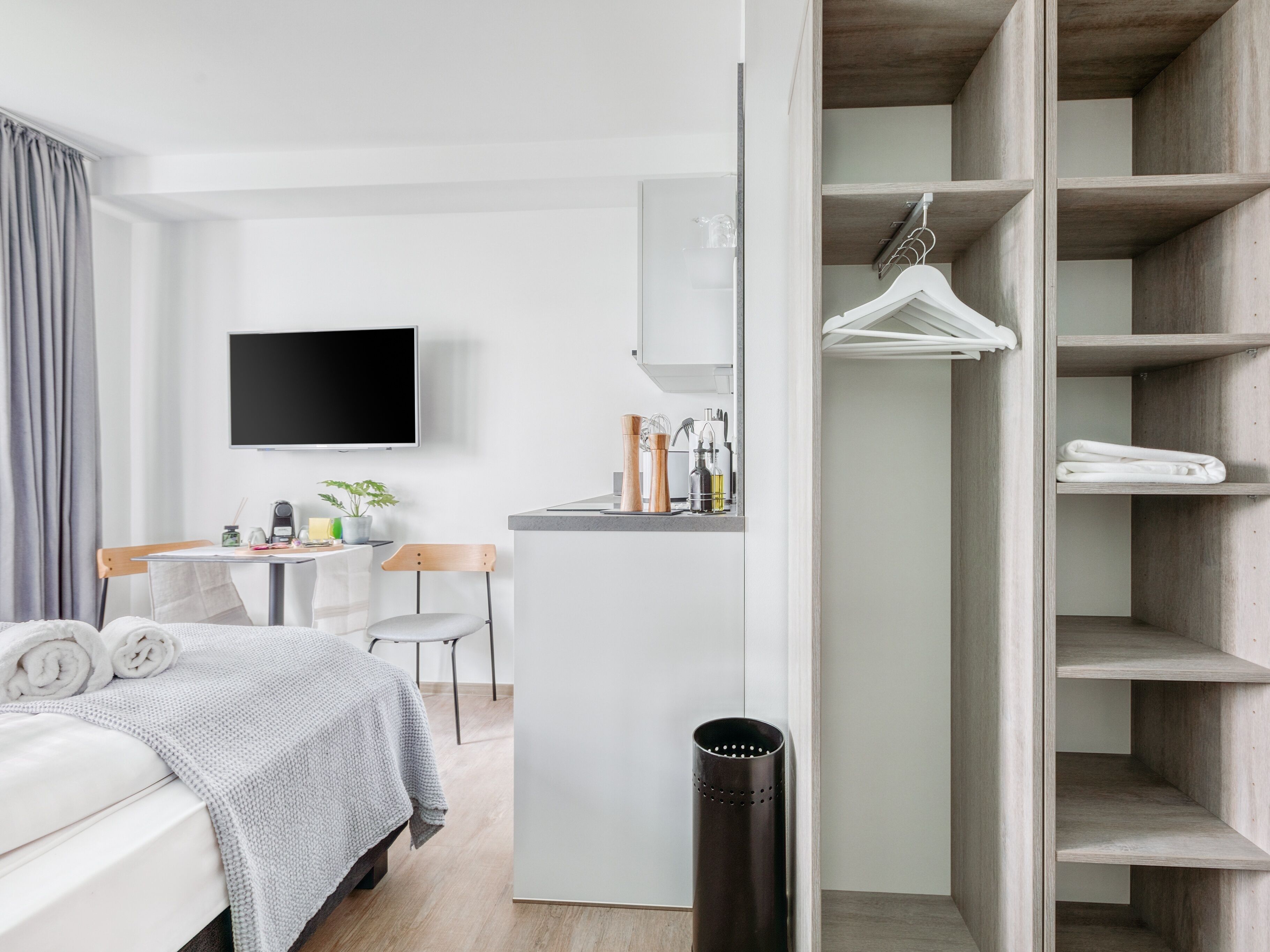 Una habitación de hotel moderna con una cama, un escritorio, un televisor y un armario.