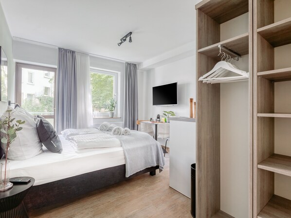 A modern bedroom with a bed, bedside table, and a TV mounted on the wall.
