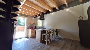 Una cocina moderna con vigas de madera, una zona de bar con taburetes y vistas al exterior.