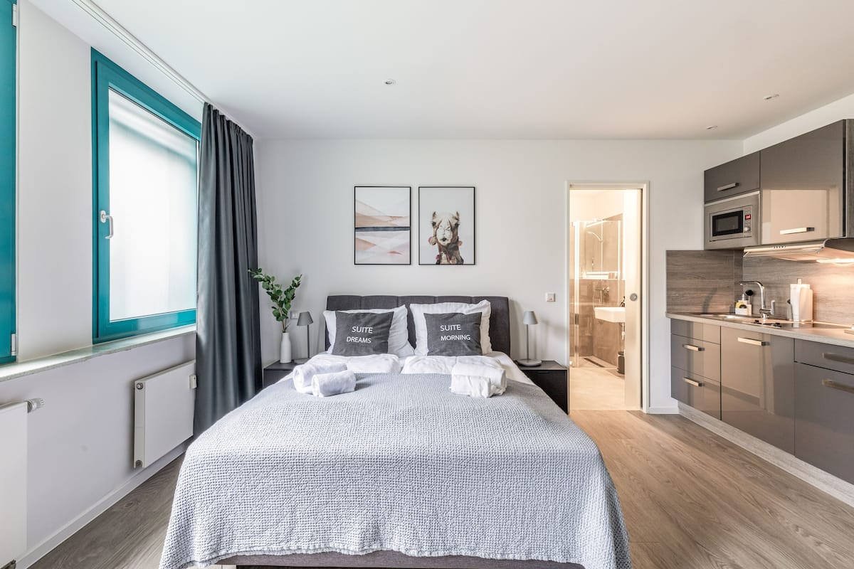 A modern bedroom with a bed, bedside tables, and a view of the bathroom.