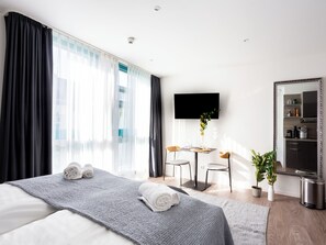 Une chambre d’hôtel moderne équipée d’un grand lit, d’un bureau, d’une télévision à écran plat et d’un miroir.