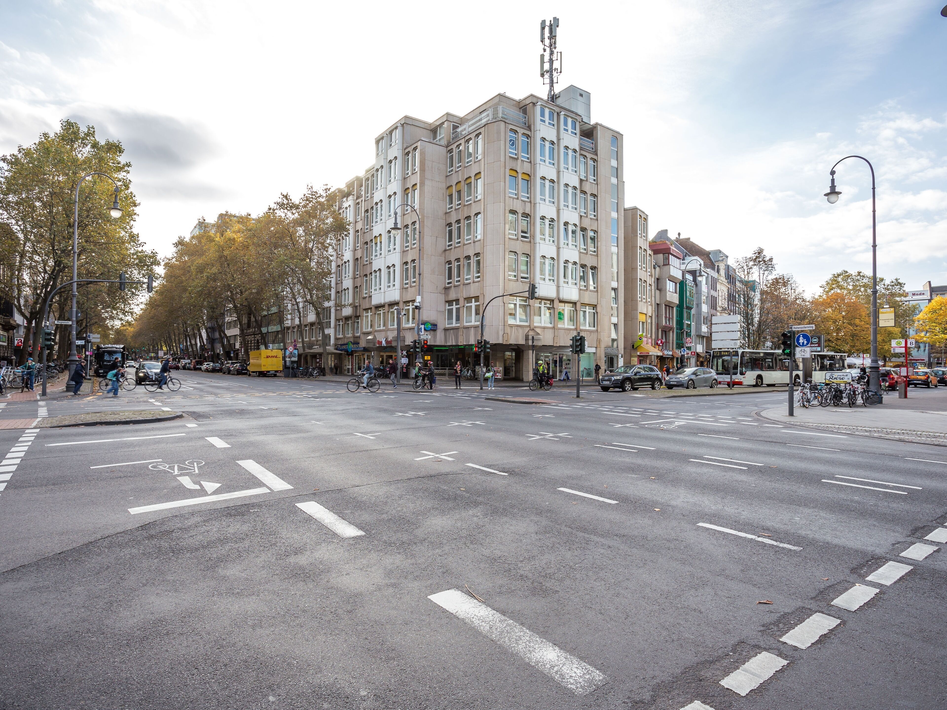Un edificio de varios pisos con un diseño arquitectónico moderno, situado en una concurrida intersección urbana.