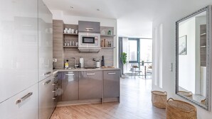 Una cocina moderna con una isla central, electrodomésticos de acero inoxidable y un espejo grande.