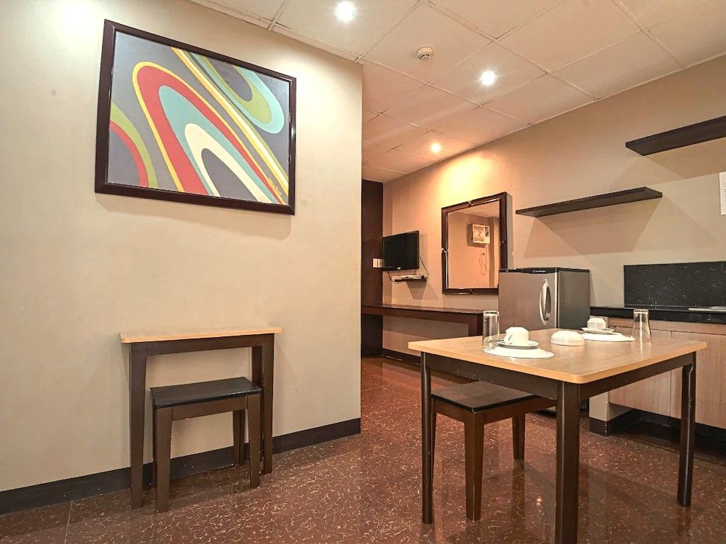 Une chambre d’hôtel avec un coin repas, une télévision et un tableau au mur.