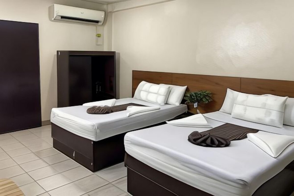 Ein Hotelzimmer mit zwei Betten, einem Kleiderschrank, einer Klimaanlage und einer Topfpflanze.