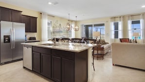 A modern kitchen with dark cabinets, a stainless steel refrigerator, and a central island.