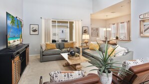 Ein Wohnzimmer mit zwei Sofas, einem Couchtisch und einem Fernseher. Auf dem Couchtisch steht eine Pflanze und auf einem Beistelltisch eine Lampe.