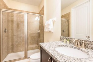 A modern bathroom with a glass-enclosed shower, a white sink, and a large mirror. - Refurbished Lux 6 Bed Golf Views at Reunion Resort by Shine Villas (Kissimmee)