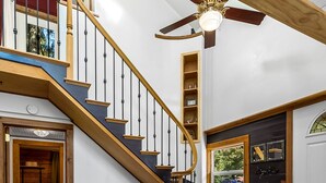 Eine Treppe mit Holzwerten und Deckenventilator, die zu einem Zwischenpodest mit Fenster und Tür führt.