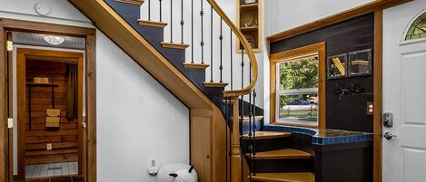 A staircase with wooden railings and a ceiling fan, leading to a landing with a window and a door.