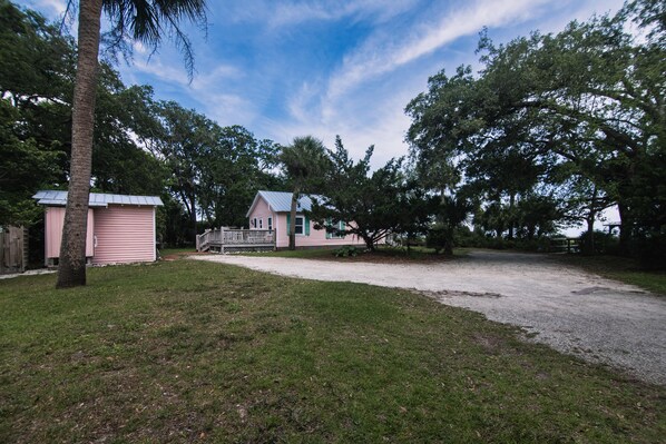 Una propiedad residencial que incluye una casa, un cobertizo pequeño y un árbol grande.