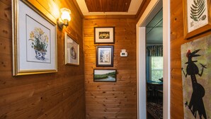 A hallway with wooden walls, framed artwork, and a thermostat. - Secluded Hideaway w/ Private Deep Water Dock; Sunrise Views; Kayaker's Paradise (Edisto Island)