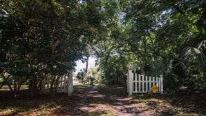 A pathway leading through a lush, green area with a white gate and a sign indicating 'ADS' and 'TOWN STREET'. - Secluded Hideaway w/ Private Deep Water Dock; Sunrise Views; Kayaker's Paradise (Edisto Island)