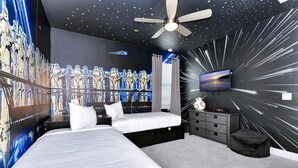 A bedroom with two beds, a ceiling fan, a TV, and a wall mural of space-themed figures. - Stylish Home near Disney: Themed Rooms, Game Room & Waterpark - 267SF (Kissimmee)