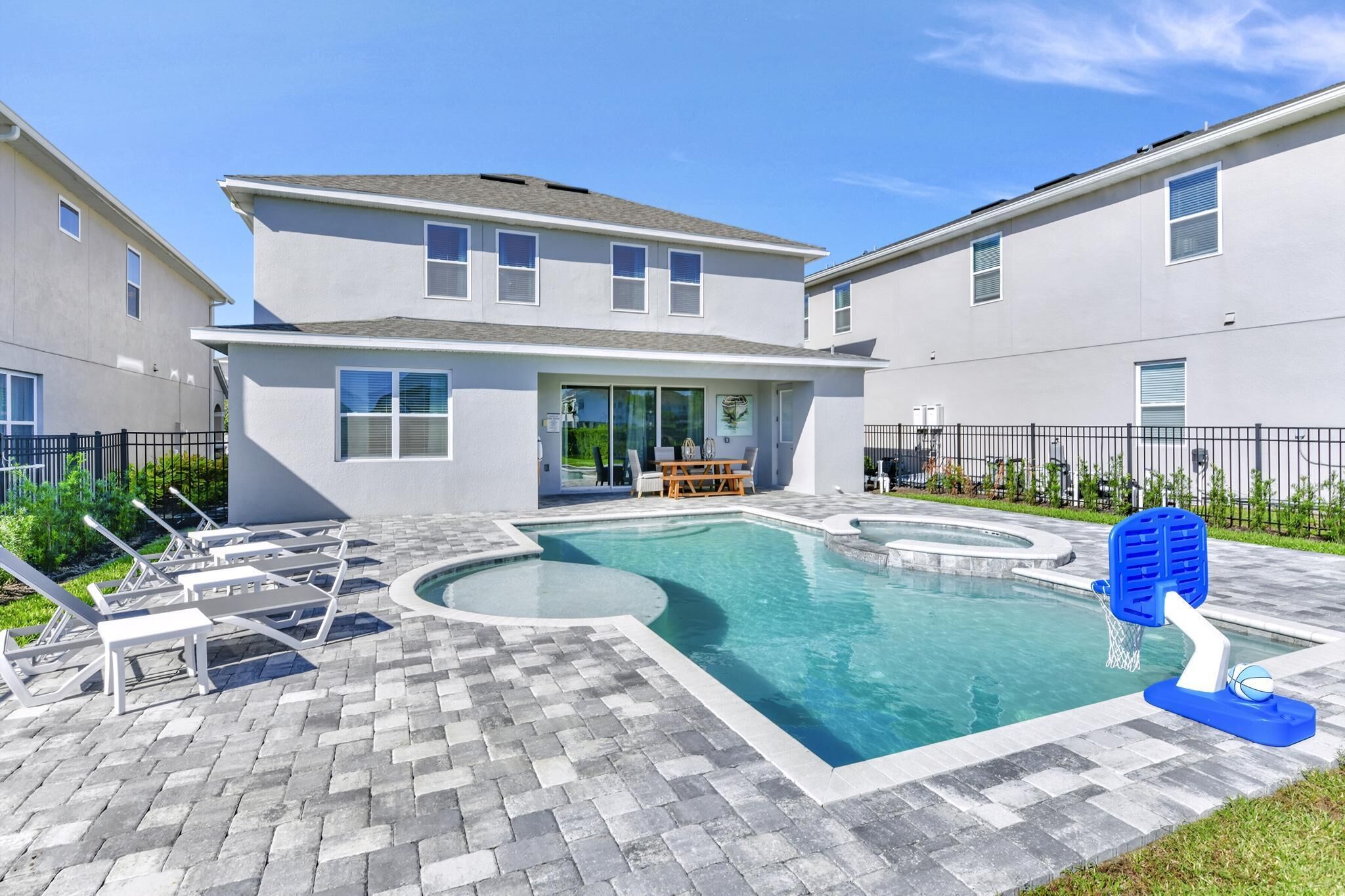 A modern residential building with a swimming pool, outdoor seating, and a basketball hoop.