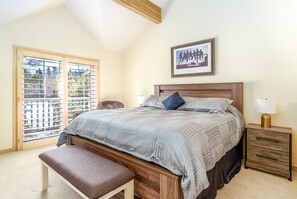A bedroom with a large bed, a bench, a nightstand, and a picture on the wall.