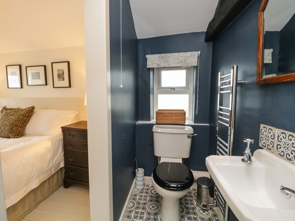 A bathroom with a toilet, sink, and window.