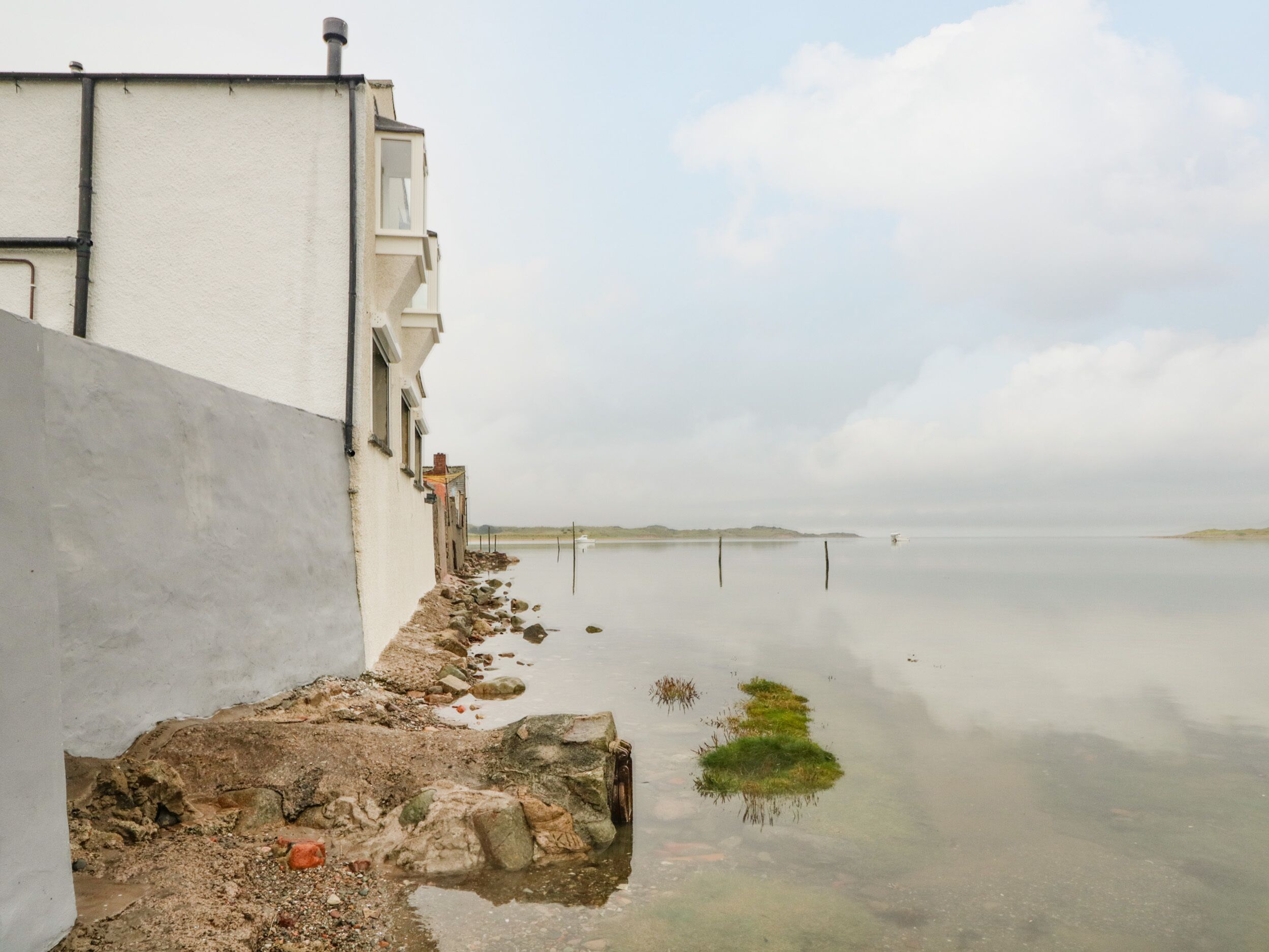 A waterfront building with a white facade and a clear view of the calm water.